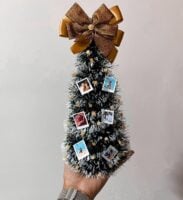 Mini árvore de Natal com pequenas fotos e laço dourado