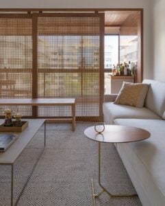 Sala de estar com sofá bege e painel grande de muxarabi