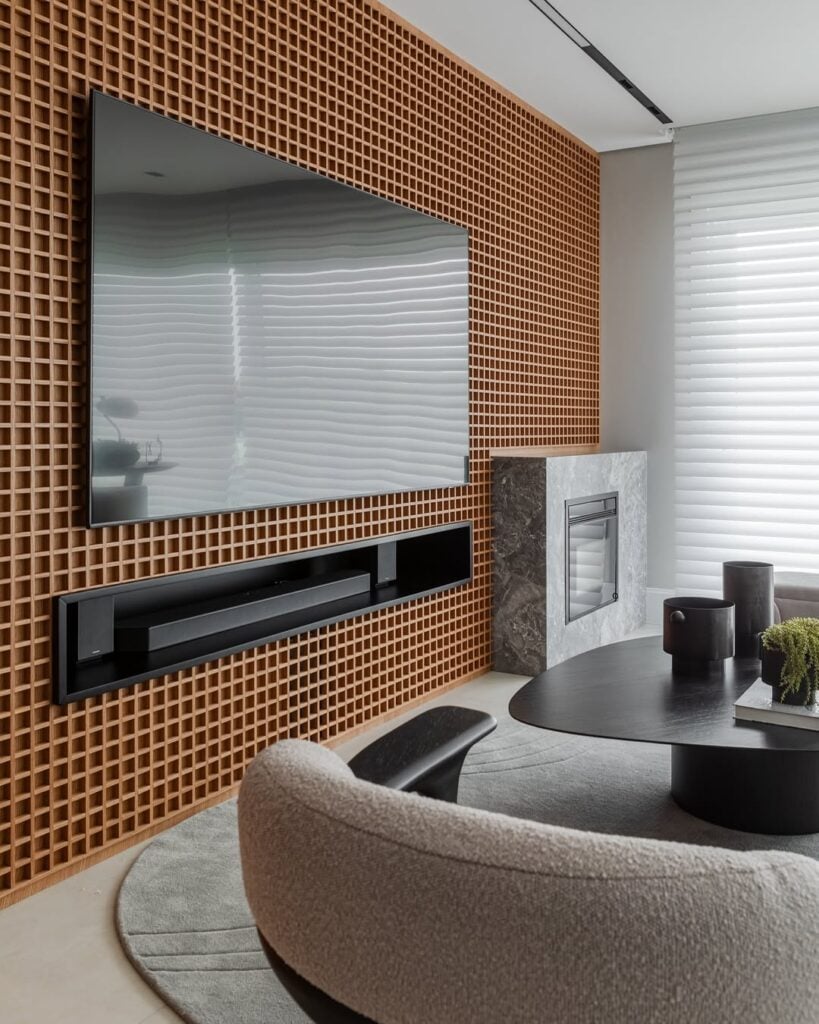 Sala com mesa de centro preta e painel de muxarabi para a tv