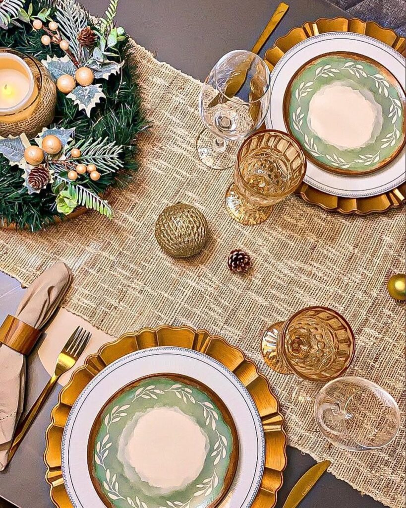 Mesa posta de Natal com trilho, sousplats e talheres dourados, pratos com detalhes verde