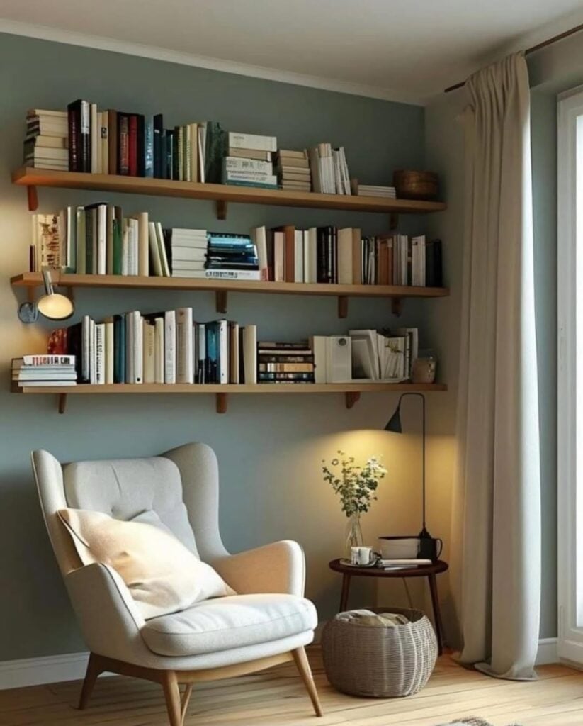 Canto da leitura com poltrona clara, mesinha lateral e prateleiras com livros