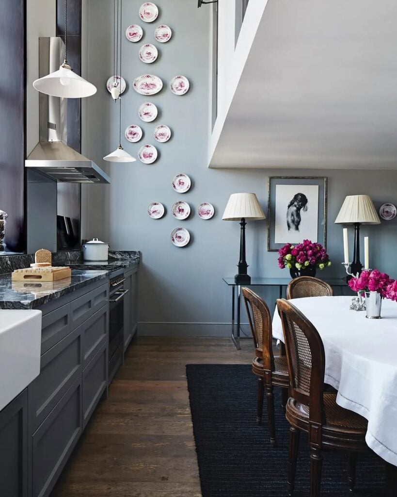 Sala de jantar com armários cinza, cadeiras de madeira e parede com pratos decorados