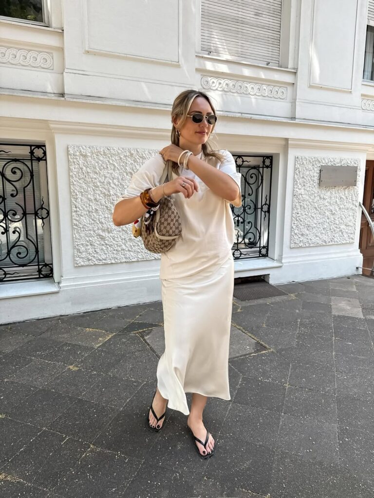 Mulher jovem usando saia midi acetinada, blusa de manga curta e chinelo preto