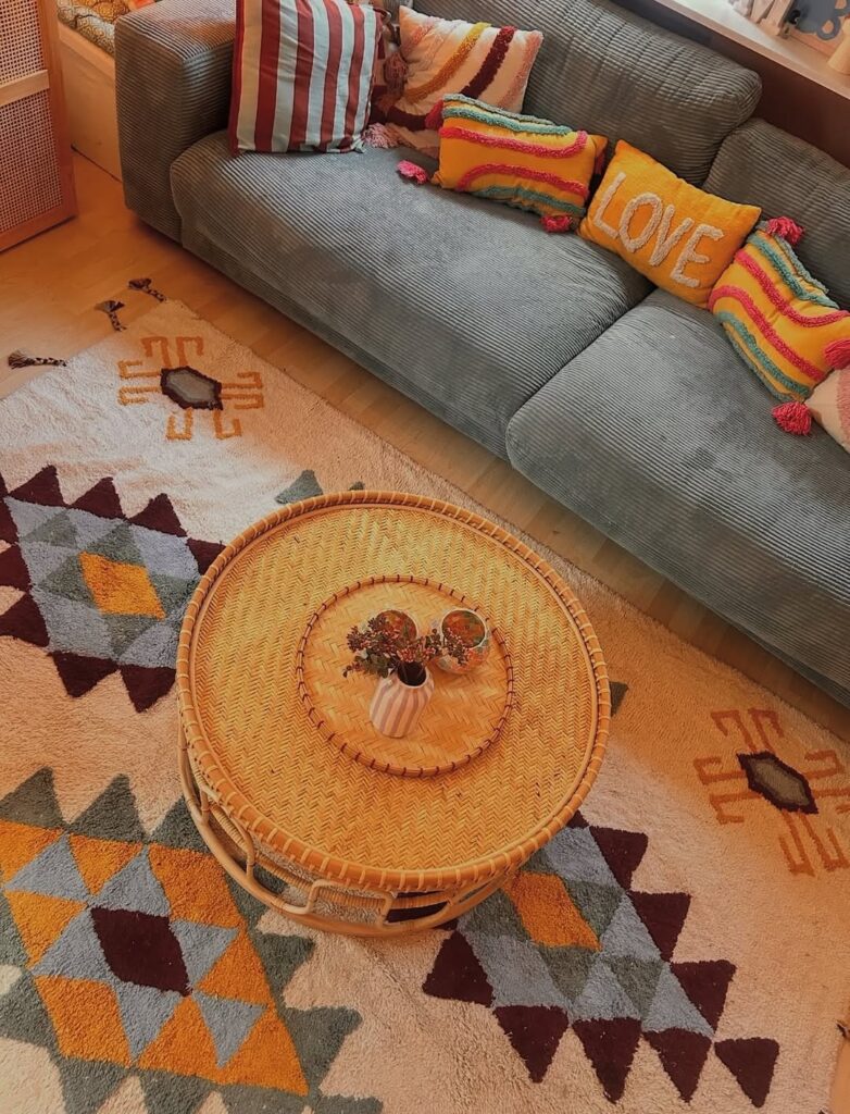 Sala com sofá cinza, almofadas coloridas e mesa de centro de palha
