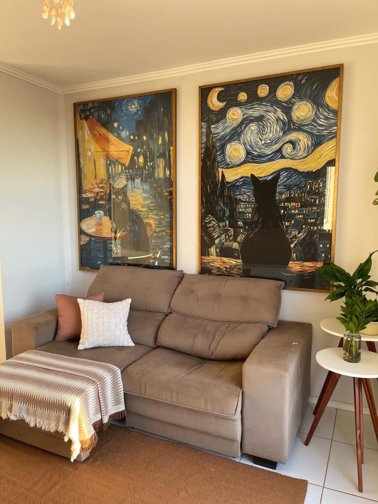 Sala com sofá de veludo cinza, mesas laterais brancas e dois quadros com gatos pretos