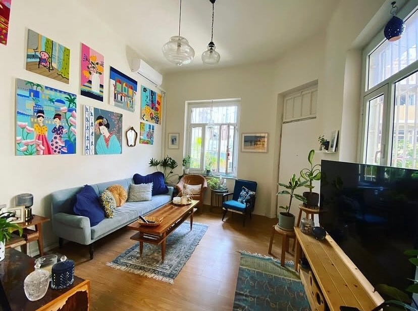 Sala de estar com sofá azul, mesa de centro de madeira e quadros coloridos