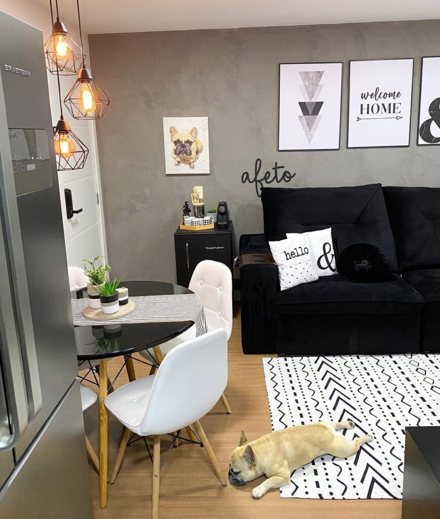 Sala com parede cinza, quadros brancos com moldura preta e sofá preto