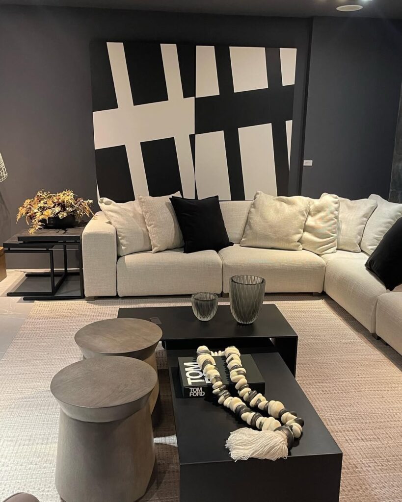 Sala de estar em preto e branco, com sofá branco, mesas de centro pretas, e quadro grande