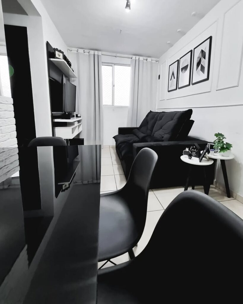 Sala pequena com paredes brancas e móveis pretos