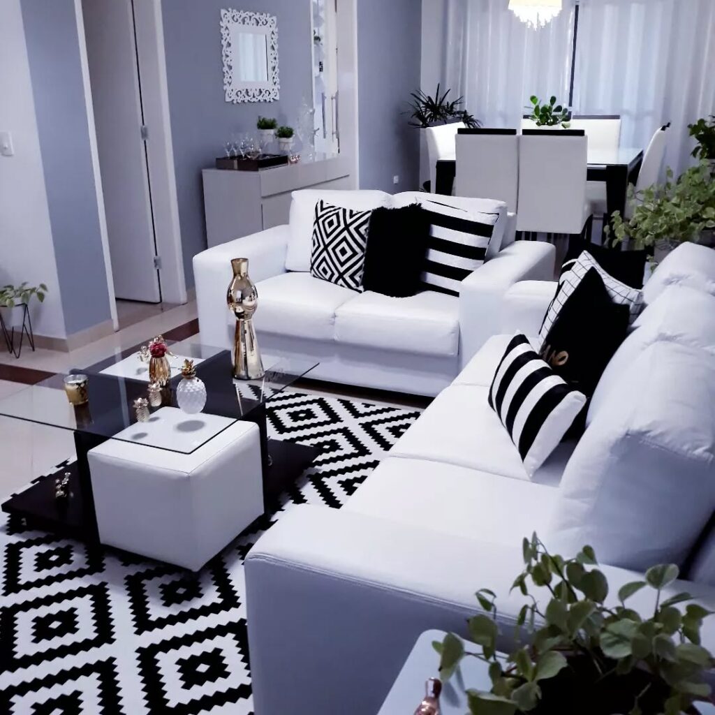 Sala de estar com sofás brancos, tapete e almofadas em preto e branco