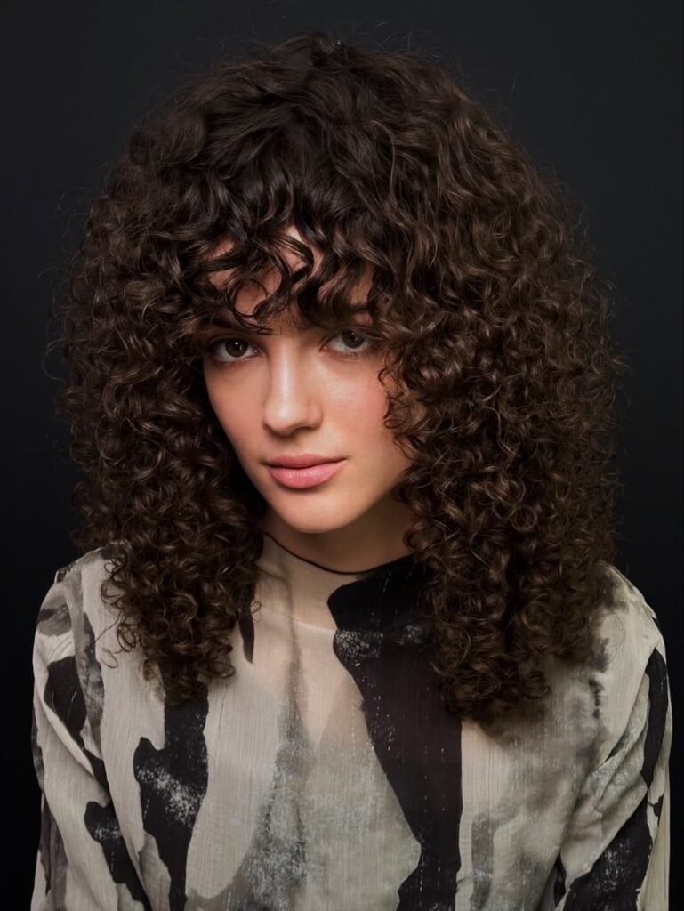 Mulher de pele clara, com cabelo cacheado com corte shaggy
