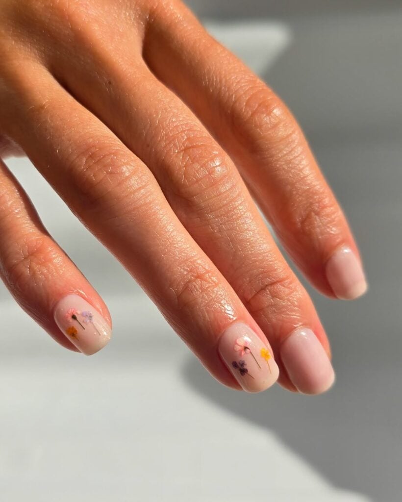 Mão de pele clara, com unha branquinha e flores para decorar