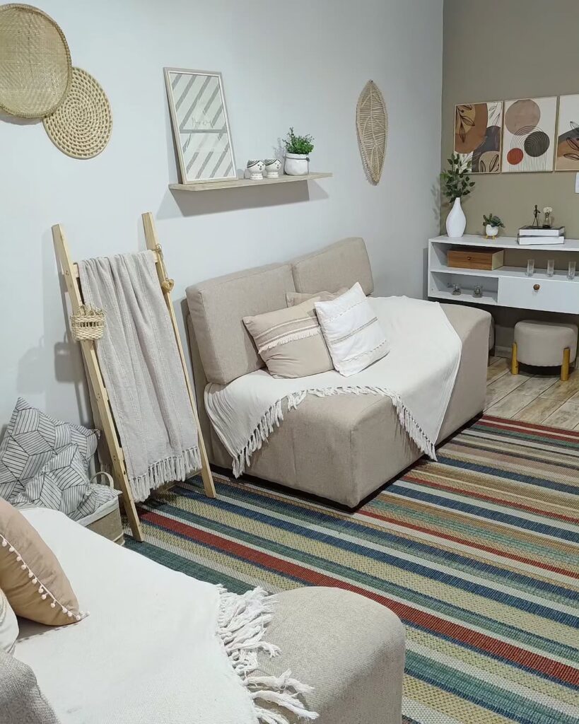 Sala de estar com sofás claros, decoração neutra e tapete listrado em tons de azul e terracota