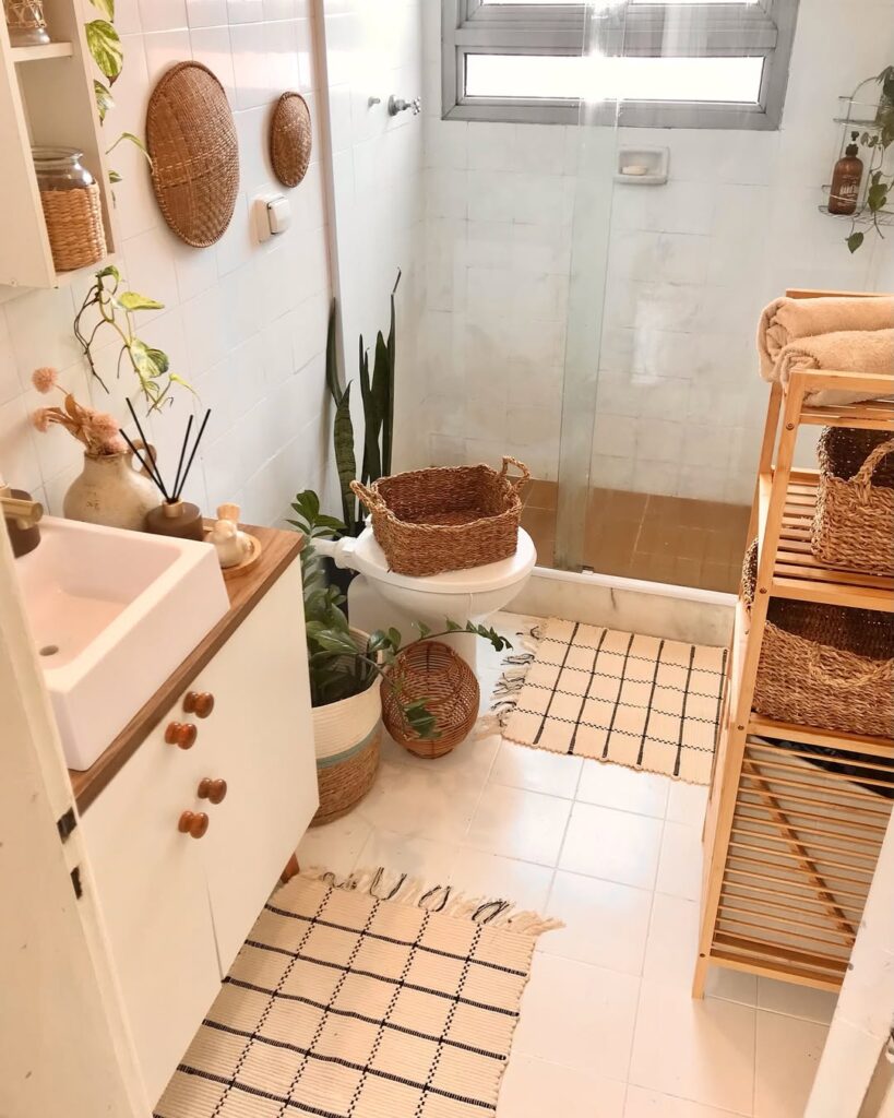 Banheiro com louças brancas, itens de materiais naturais e tapetes boho