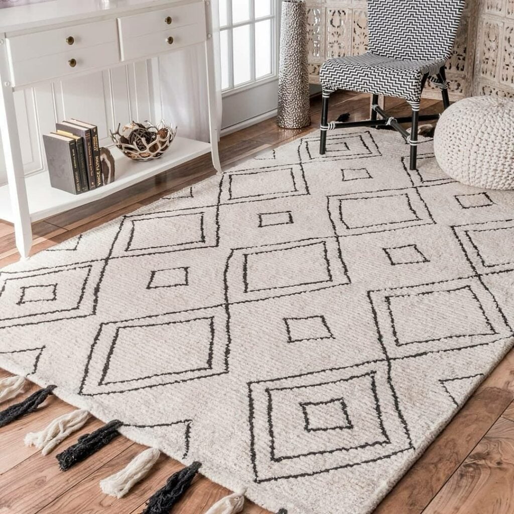 Ambiente com aparador branco, pufe de crochê, cadeira em branco e preto e tapete boho grande