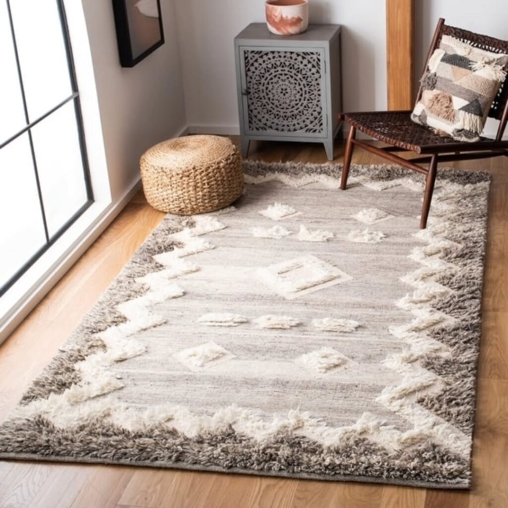 Ambiente com cadeira marrom, pufe de materiais naturais e tapete retangular boho