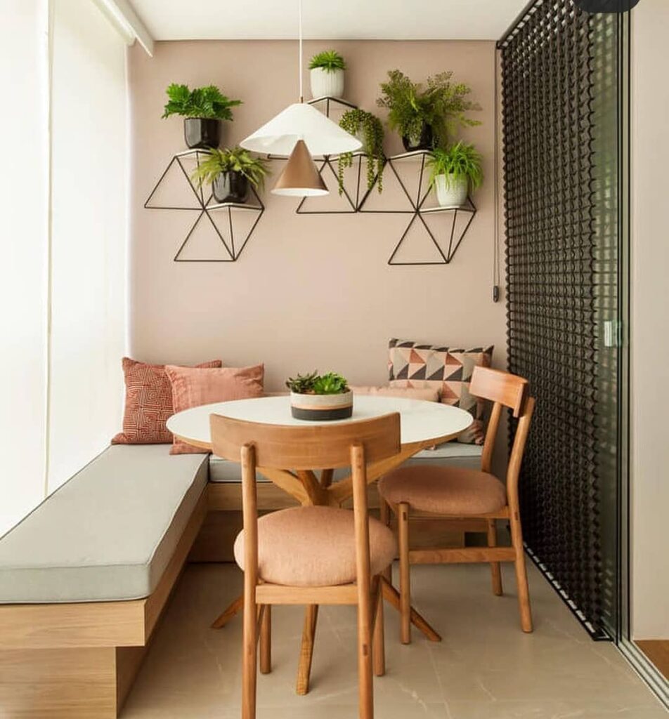 Varanda com mesa e cadeiras e banco no estilo canto alemão com pendente e plantas na parede
