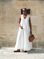 Mulher jovem, magra e de pele negra com vestido longo branco