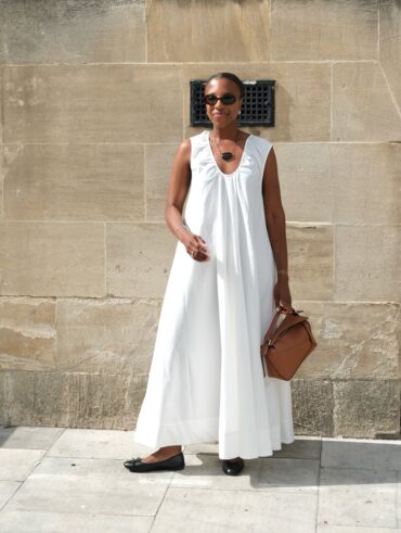 Mulher jovem, magra e de pele negra com vestido longo branco