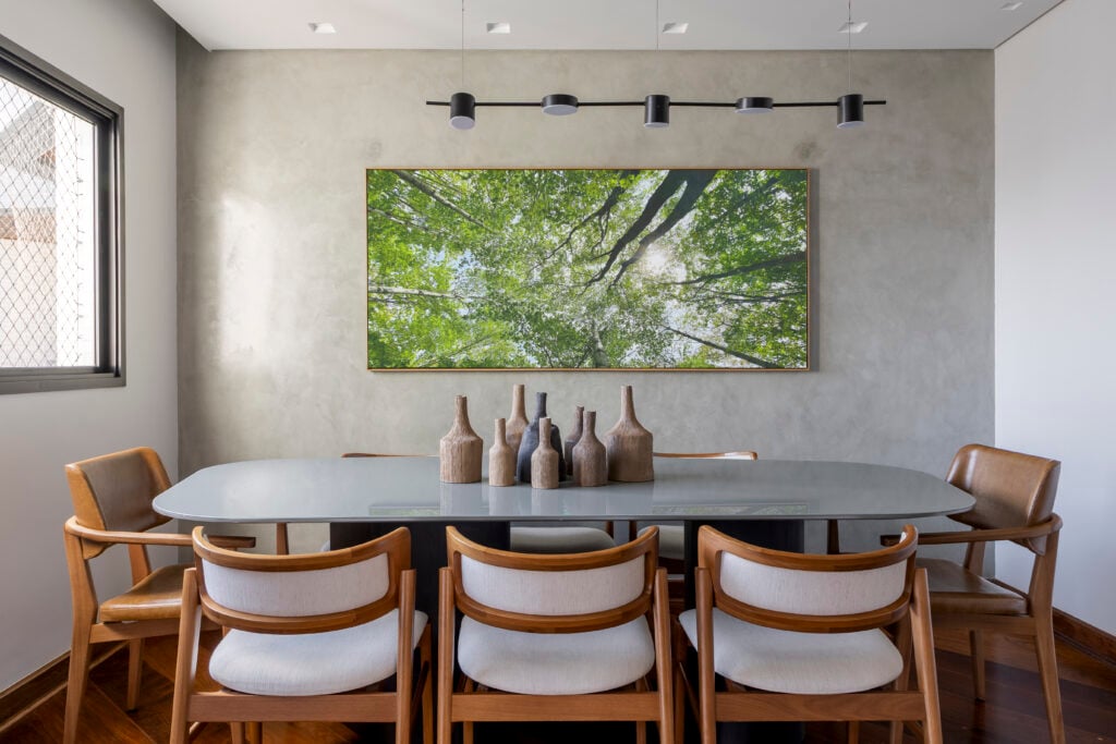 Sala de jantar com mesa cinza e cadeiras em madeira com estofado claro
