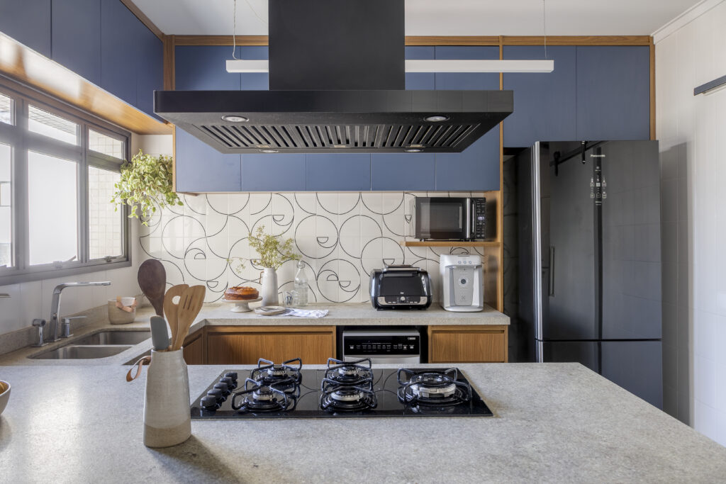 Cozinha com armários azuis, frontão claro com desenhos em preto