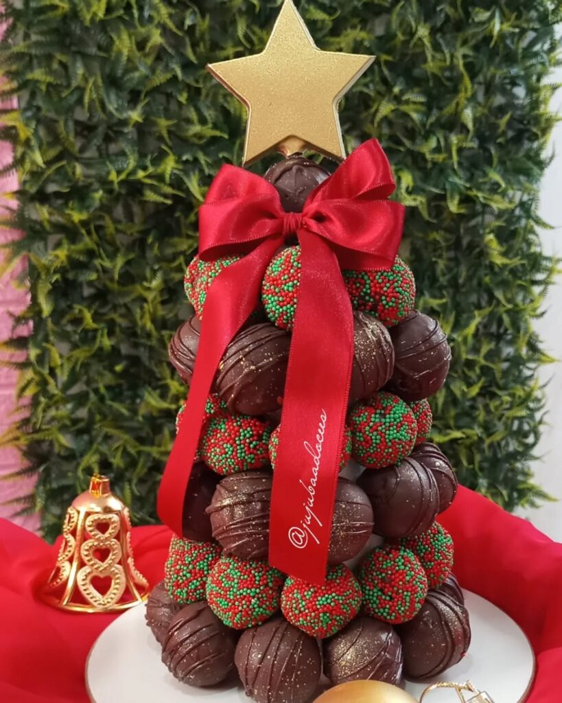 Árvore de Natal com brigadeiros de chocolate e coloridos com laço vermelho e estrela dourada no topo