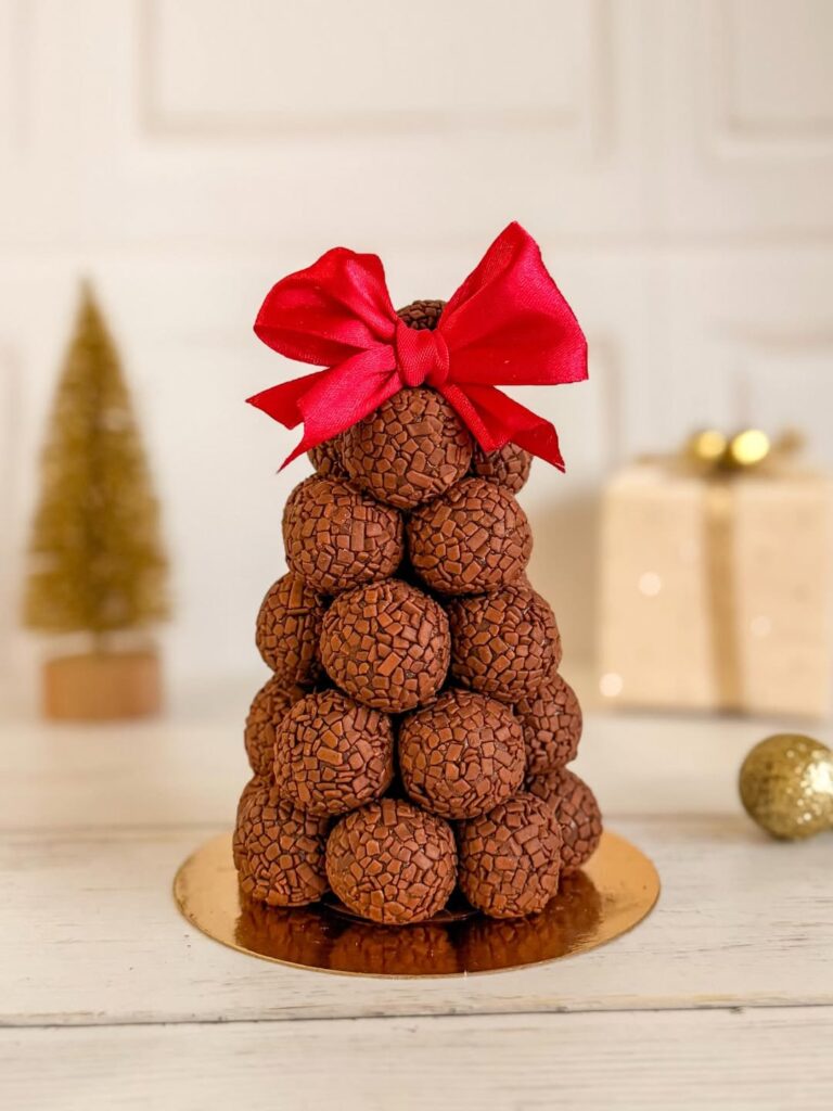 Árvore com brigadeiros empilhados e um laço vermelho no topo