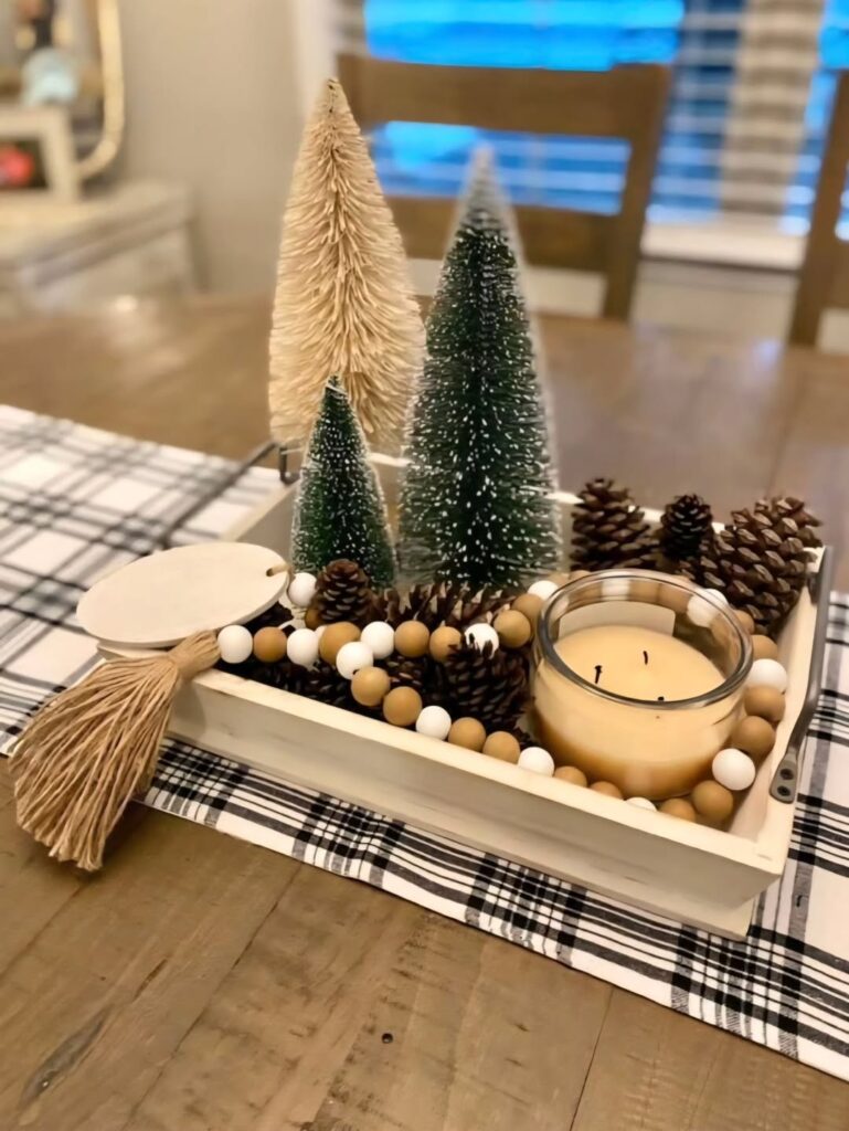 Bandeja retangular bege com vela, pinhas e mini árvores de Natal