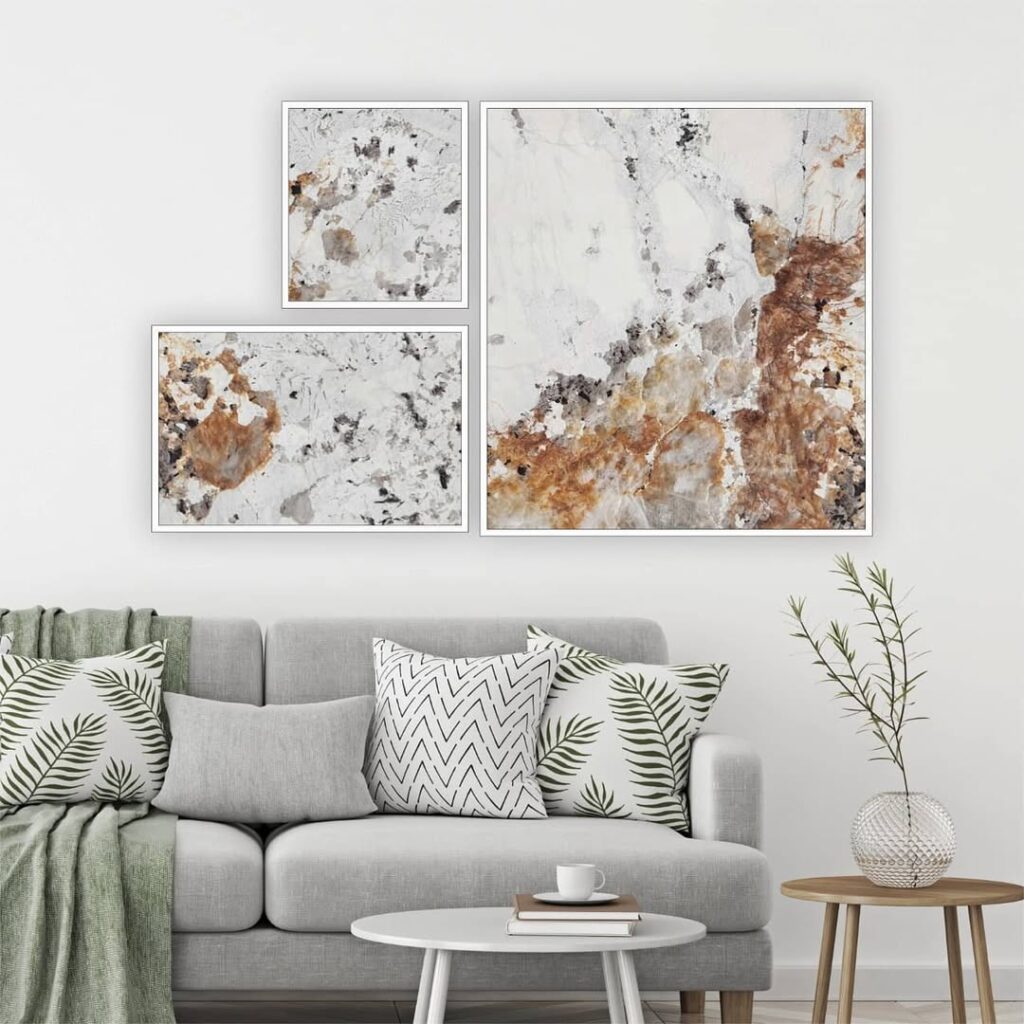 Sala com sofá cinza, almofadas, manta e quadros abstratos na parede