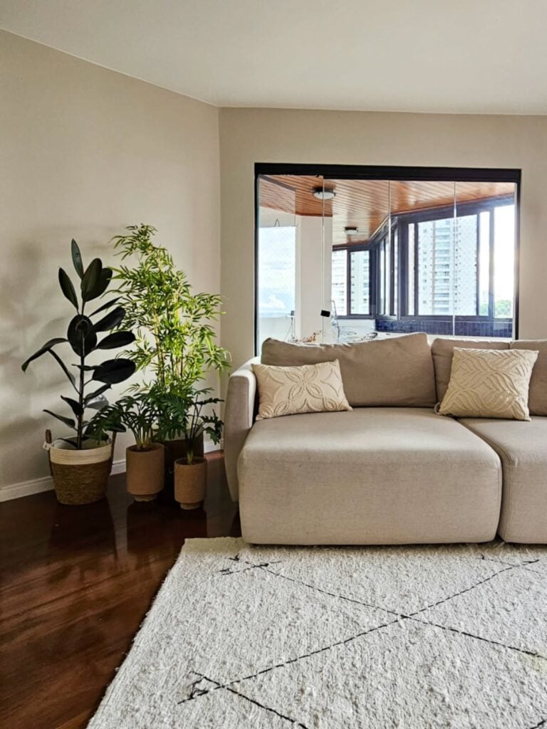 Sala com sofá claro e plantas grandes em vasos no canto