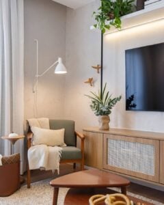 Canto de sala com poltrona, almofada, mantinha e arandela