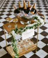 Carrinho de bar dourado com taças e espumantes