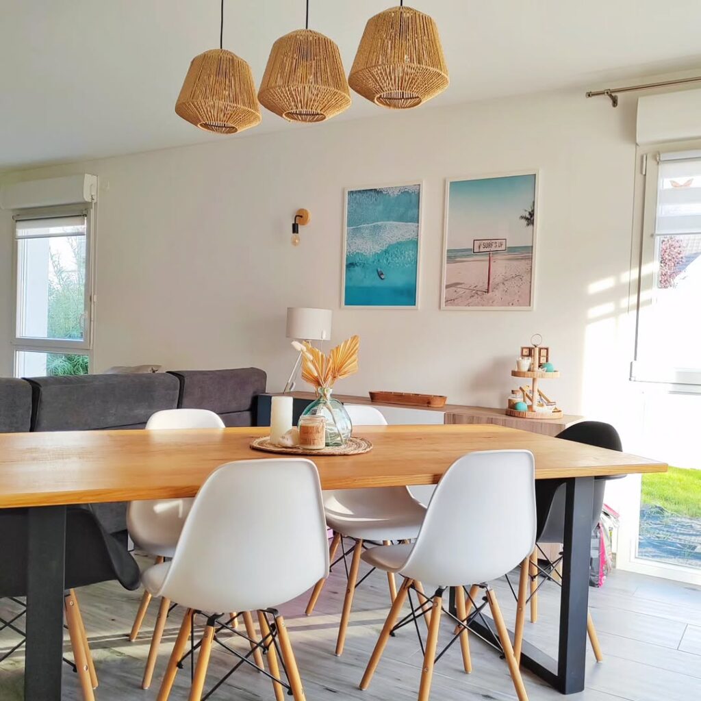 Sala de jantar com mesa retangular e cadeiras brancas, e pendentes de fibras naturais
