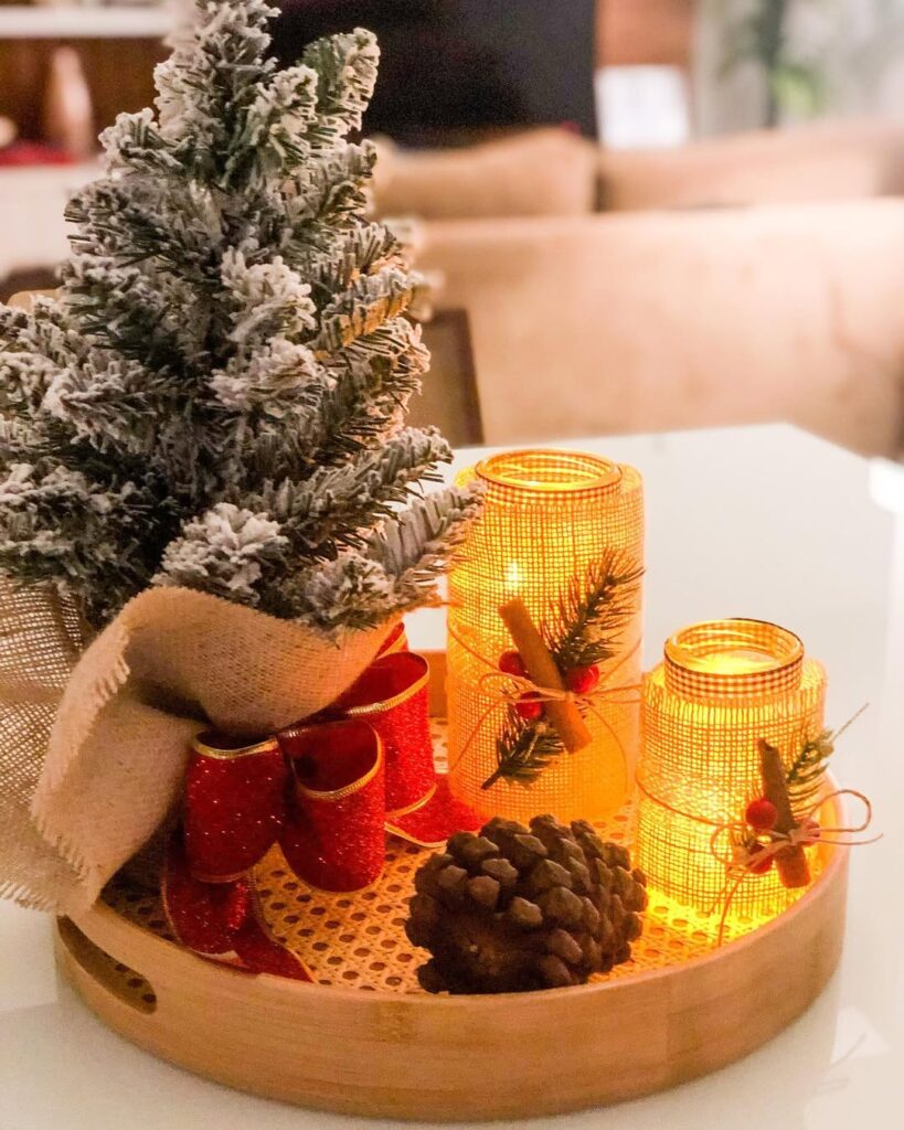 Bandeja de bambu com potes e velas, pinha, ramo verde com laço vermelho