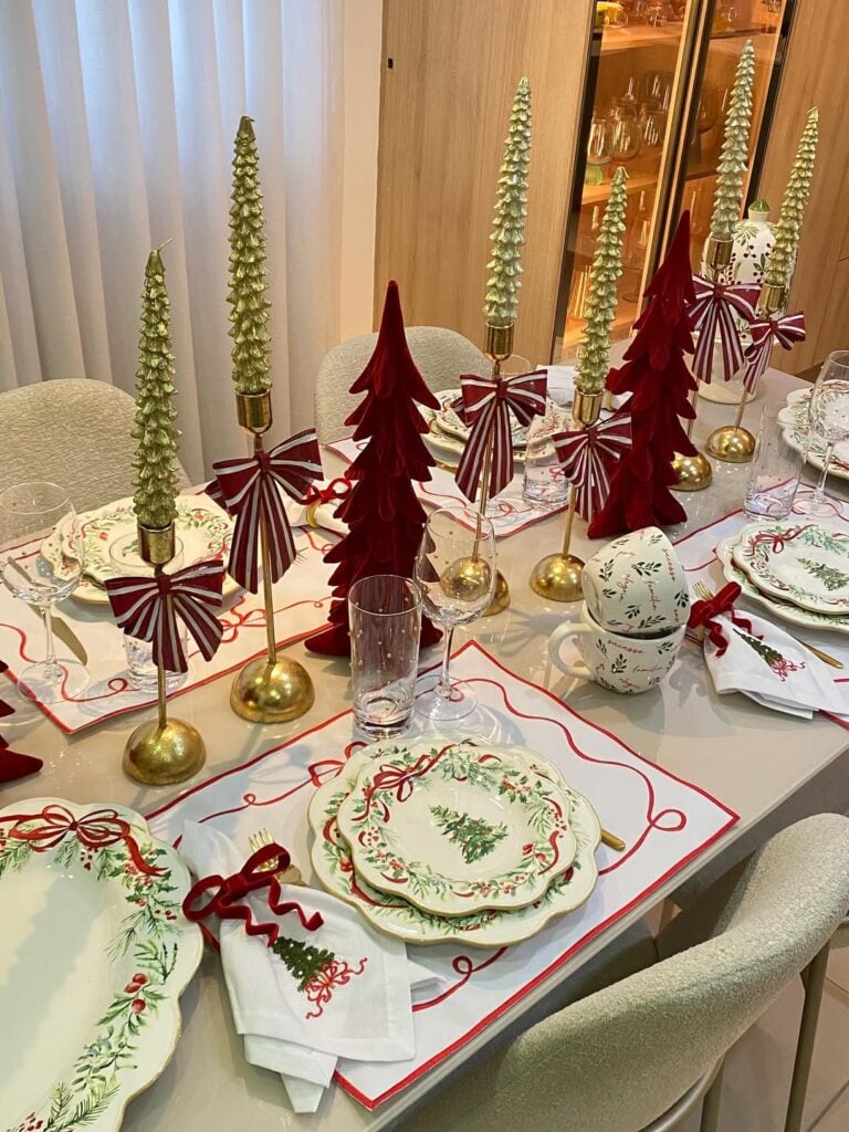 Mesa posta de Natal com árvores vermelhas e castiçais dourados
