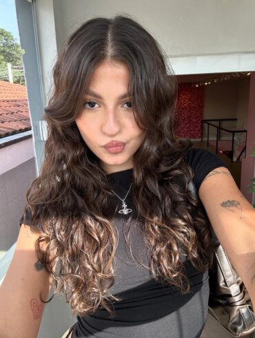Mulher de pele clara, com blusa preta e cabelo ondulado escuro