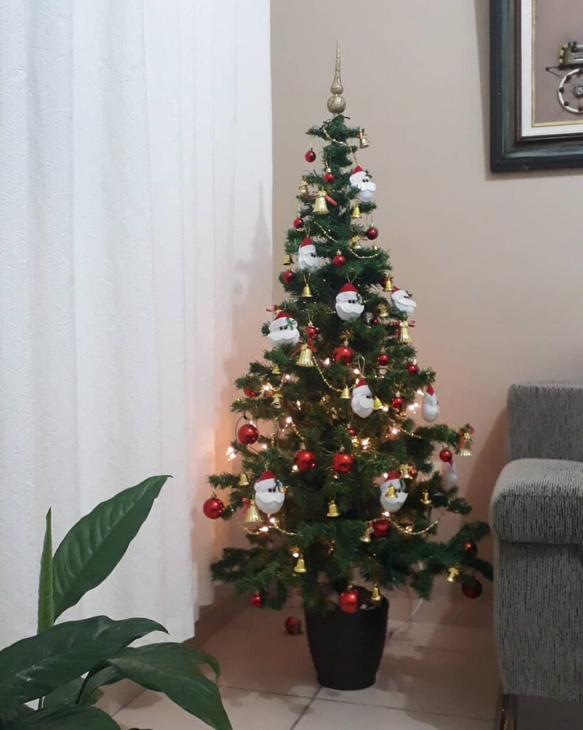 Árvore de Natal decorada com sinos dourados, bolinhas vermelhas e Papais Noeis