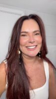 Mulher de pele clara, com blusa branca, cabelo longa escuro e maquiagem leve