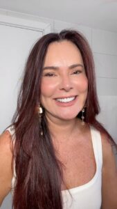 Mulher de pele clara, com blusa branca, cabelo longa escuro e maquiagem leve