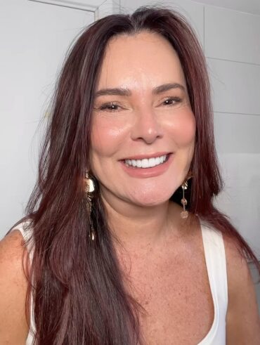 Mulher de pele clara, com blusa branca, cabelo longa escuro e maquiagem leve