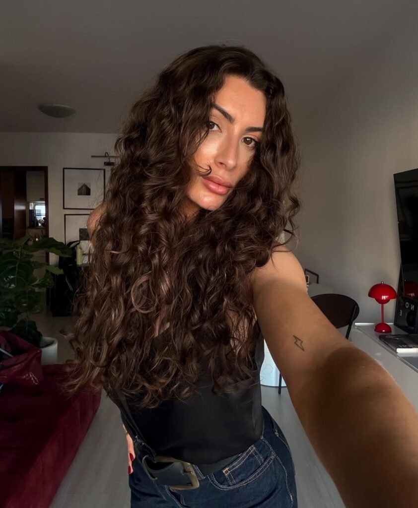 Mulher de pele clara, com cabelo ondulado com corte em camadas