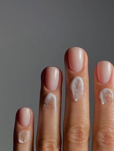 Mão de pele clara, com unha curta neutra e creme nas cutículas