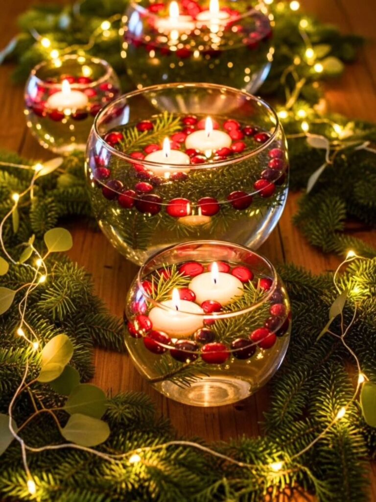 Recipientes de vidro com ramos verdes, frutinhas vermelhas e velas