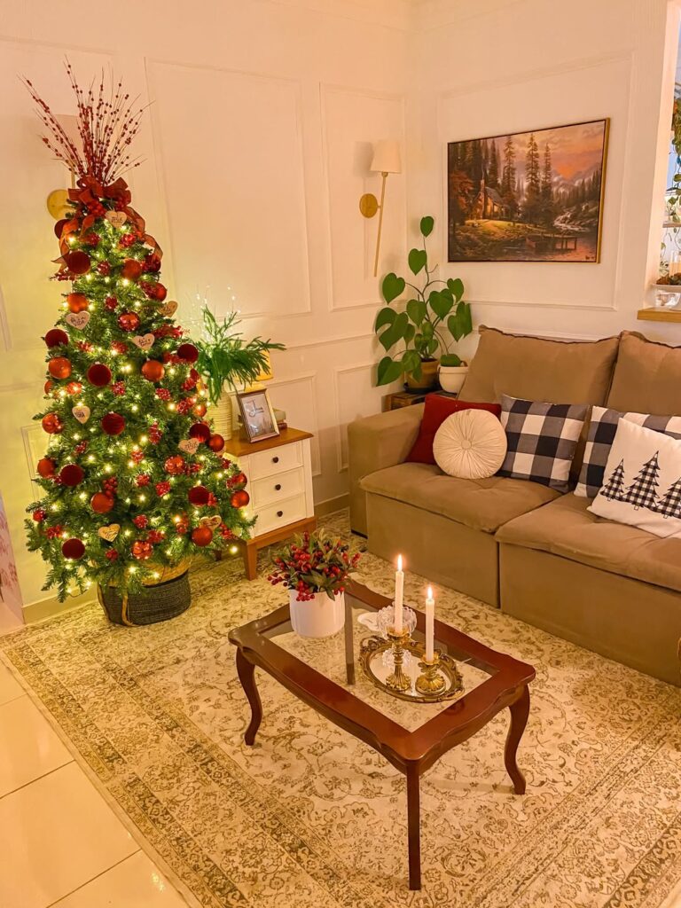 Sala de estar com sofá em tom de marrom, almofadas variadas, árvore de Nal no canto nas cores vermelho e dourado