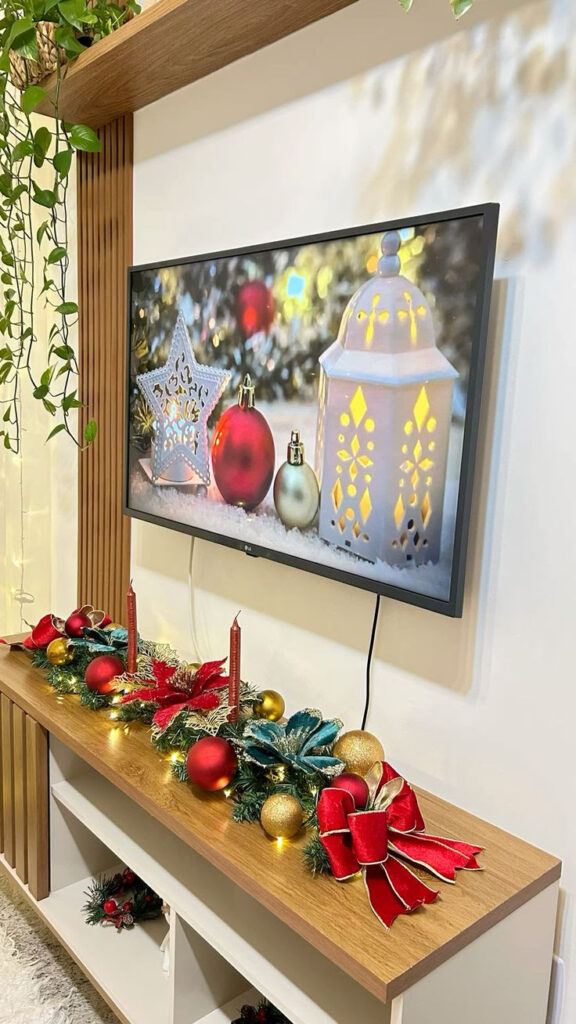 Rack de tv com arranjos natalinos em cores vermelho, dourado e verde