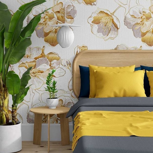 Quarto tropical com cama de madeira, almofadas amarelas, papel de parede com flores e vaso com planta grande