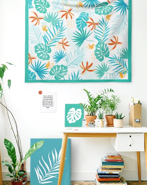 Aparador com bancada branca, vasos de plantas, moldura de pano azul com flores e folhas coloridas
