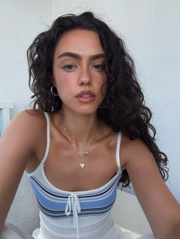 Mulher de pele clara, com regata listrada e cabelo cacheado escuro