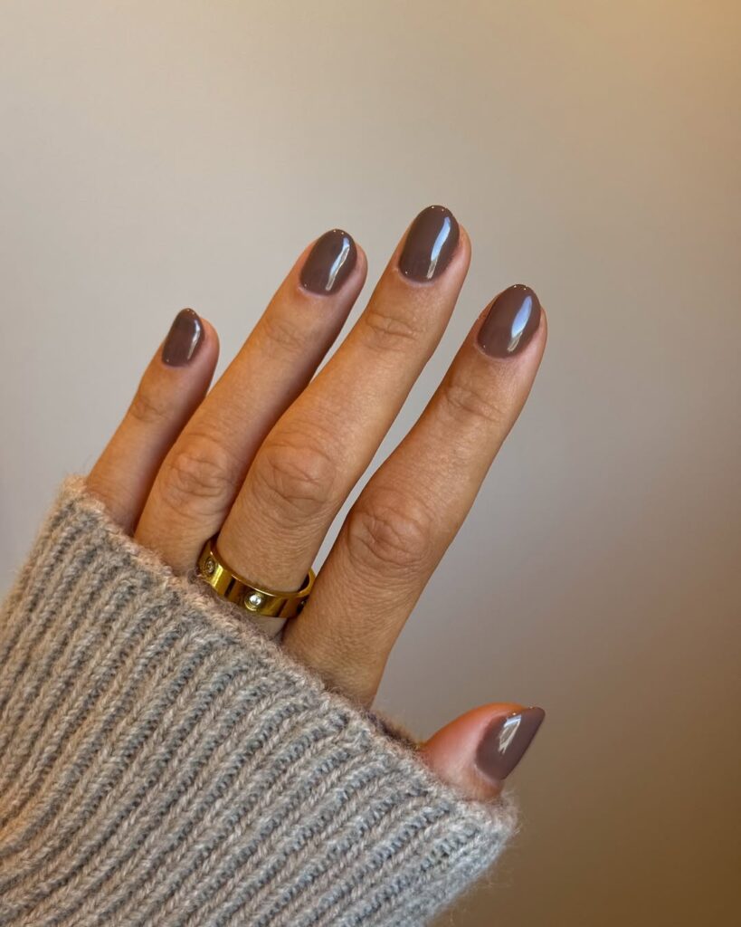 Mão de pele clara, com anel dourado e unha curta marrom