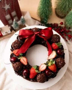 Guirlanda de chocolate com brigadeiros, morangos, cerejas e laço vermelho